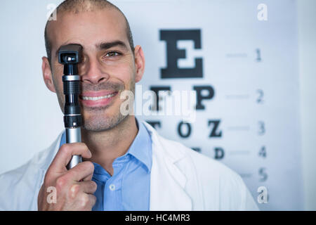 All'ottico optometrista cerca attraverso oftalmoscopio Foto Stock