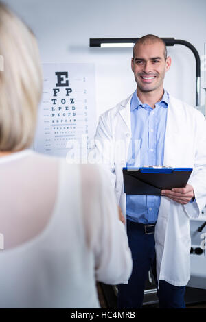 Maschio all'ottico optometrista parlando al paziente di sesso femminile Foto Stock