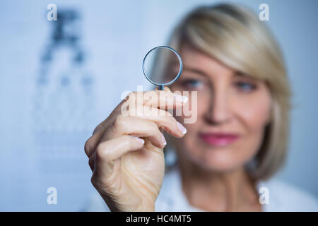 All'ottico optometrista femmina tenendo la lente di ingrandimento Foto Stock