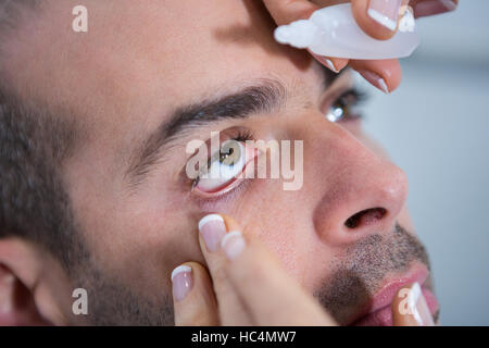 All'ottico optometrista mettendo scende in pazienti occhi Foto Stock