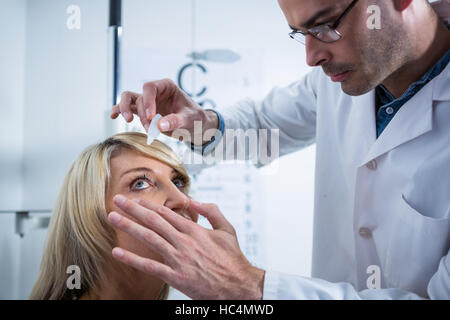 All'ottico optometrista mettendo scende in pazienti occhi Foto Stock