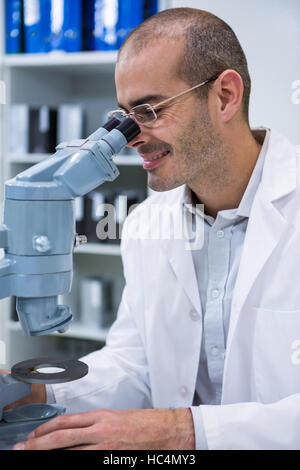Maschio sorridente all'ottico optometrista guardando attraverso il microscopio Foto Stock