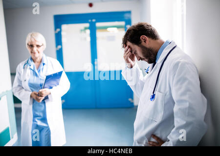 Triste medico appoggiata contro il muro Foto Stock