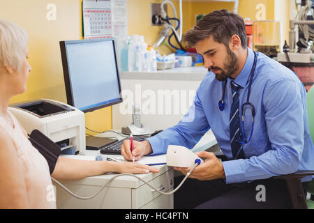 Medico controllando la pressione del sangue del paziente Foto Stock