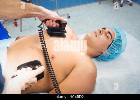 Chirurgo maschio resuscita un inconscio di un paziente con un defibrillatore Foto Stock