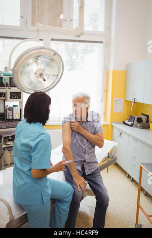 Medico donna dando una iniezione di un paziente Foto Stock