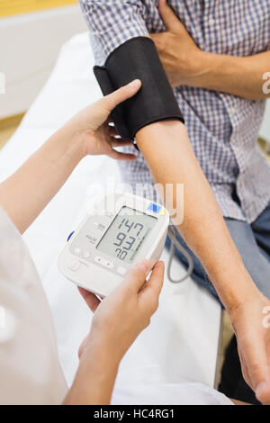 Medico donna controllando la pressione del sangue del paziente Foto Stock