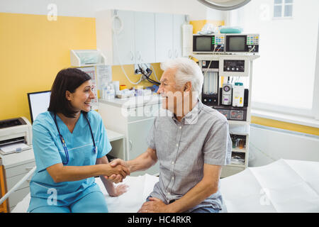Medico donna stringono le mani con paziente Foto Stock
