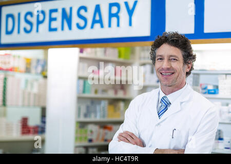 Il farmacista in piedi con le braccia incrociate in farmacia Foto Stock