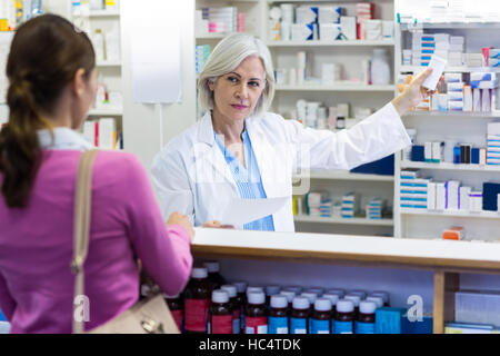 Il farmacista che mostra il flacone di farmaco per il cliente Foto Stock