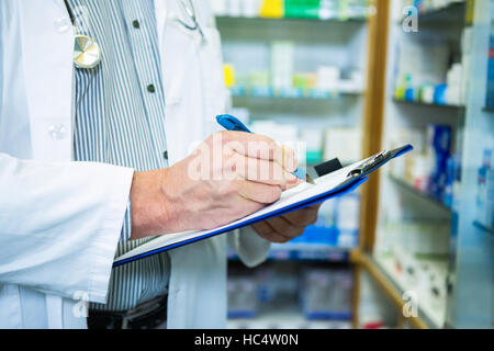 Il farmacista iscritto negli appunti in farmacia Foto Stock