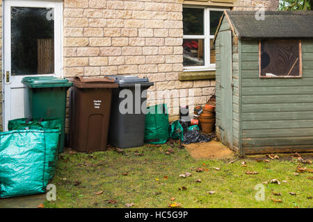 Tettoia da giardino, cassonetti, cassonetti per il riciclaggio e il giardino i sacchetti dei rifiuti schierate dal garage in un giardino privato - West Yorkshire, GB. Foto Stock