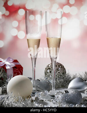 Due bicchieri di champagne per celebrare il Natale con il rosso della decorazione e regalo Foto Stock
