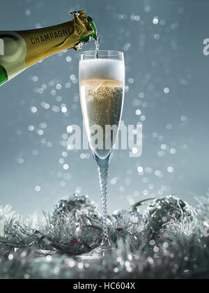 Versando champagne in vetro su un blu sullo sfondo di Natale Foto Stock