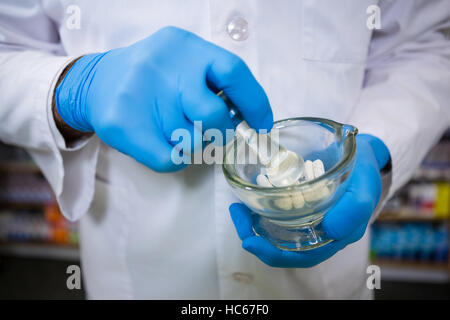 Il farmacista medicina di molatura con mortaio e pestello Foto Stock