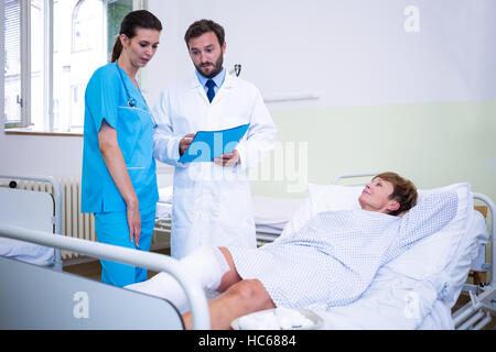 Medico e infermiere discutendo su paziente s gamba Foto Stock