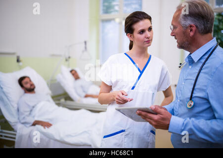 Medico e infermiere discutendo su tavoletta digitale Foto Stock