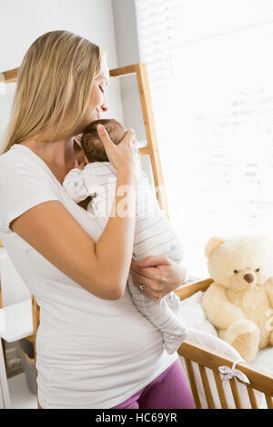 Sorridente madre che porta il suo bambino Foto Stock