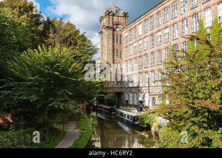 Clarence Mill - un vecchio mulino di seta - sulle rive del canale a Macclesfield in Bollington Cheshire con ormeggiate imbarcazioni strette. Foto Stock