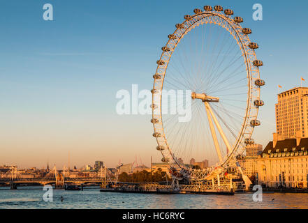 Il London Eye e il London e il fiume Tamigi skyline nel pomeriggio il sole d'inverno. Il London Eye è impostata contro un cielo blu. Foto Stock
