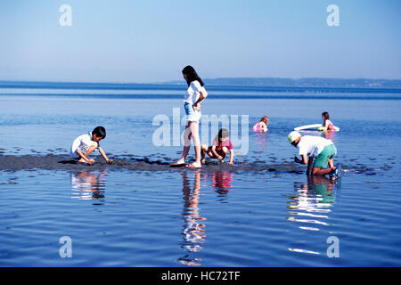 I bambini a giocare all'aperto in acqua dell'Oceano Pacifico e la baia di confine del Parco Regionale del Delta, BC, British Columbia, Canada Foto Stock