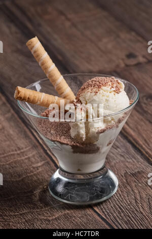 Gelato alla crema con cioccolato e cookie in vetro su un tavolo di legno. Angolo di visione. Foto Stock