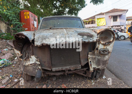 Vecchia auto arrugginito, abbandonato e spogliato dei suoi proiettori sul lato della strada in Panjim, Goa, India Foto Stock
