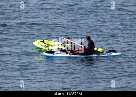 Due persone che sono caduti al di fuori di un kayak in mare Foto Stock