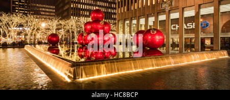 Rossa gigante ornamenti di Natale sulla 6th Avenue con la stagione delle feste decorazioni. Midtown. La città di New York Foto Stock