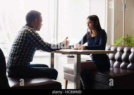 Scena in cafe - giovane conflitto sostenendo durante il pranzo. Foto Stock