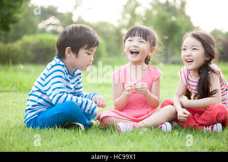 Tre bambini sorridenti seduta sul campo Foto Stock