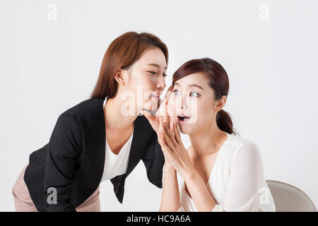 Due giovani imprenditrici sorridente parlando in un sussurro Foto Stock