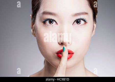 Ritratto di giovane donna Coreana di mettere il suo dito sul suo labbro Foto Stock