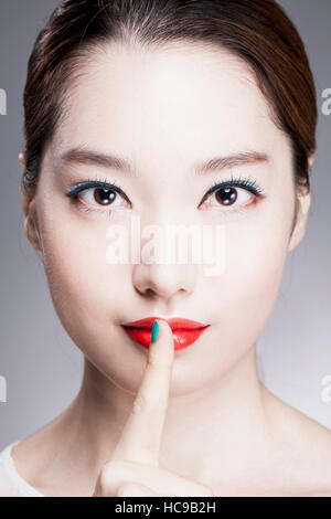 Ritratto di giovane donna Coreana di mettere il dito sulle sue labbra rosse Foto Stock