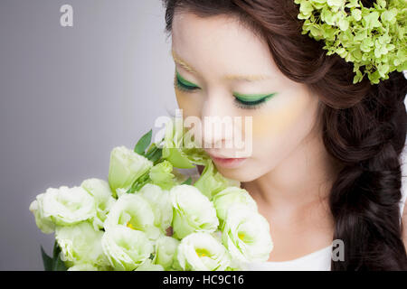 Ritratto di giovane sorridente donna coreana profumati fiori Foto Stock