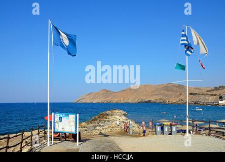 Le bandiere e le schede di informazione sul bordo della spiaggia con vista verso la costa rocciosa, Panormos, Creta, Grecia, l'Europa. Foto Stock