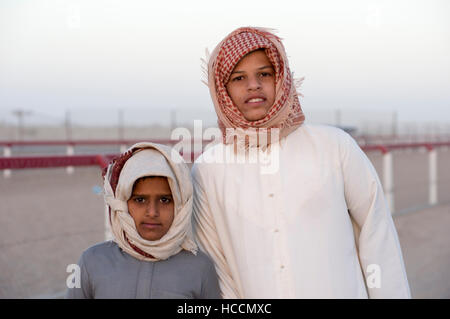 Due ragazzi che indossa Omani sciarpe di testa a margine di una corsa di cammelli in Oman Foto Stock