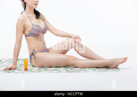 Vista laterale del giovane slim donna seduta sul telo da spiaggia Foto Stock