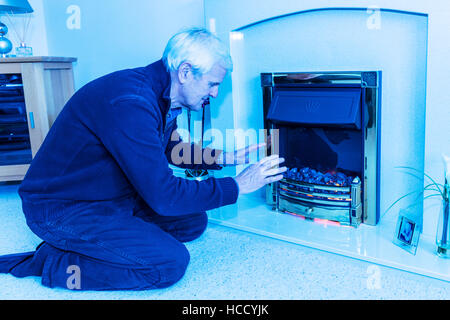 OAP cercando di mantenere caldo il riscaldamento le mani vicino al fuoco conservando le fatture verso il basso non può permettersi il riscaldamento bill elevata di gas le bollette di energia REGNO UNITO Inghilterra Foto Stock