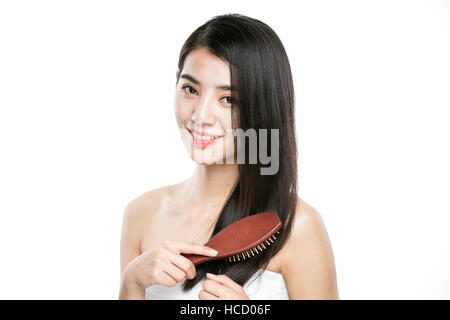 Ritratto di giovane donna sorridente spazzolando i suoi lunghi capelli dritti Foto Stock
