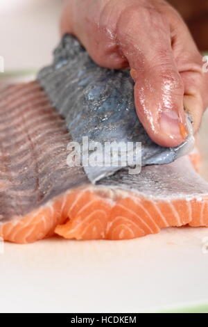 Rimuovere la pelle dal filetto di salmone. Rendendo il salmone in pasta sfoglia serie. Foto Stock