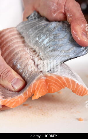 Rimuovere la pelle dal filetto di salmone. Rendendo il salmone in pasta sfoglia serie. Foto Stock