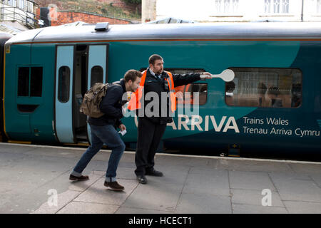 Guardia circa a wave off Galles arriva in treno, la stazione di Shrewsbury è a Foto Stock