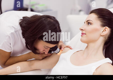 Il dermatologo esaminando la pelle del paziente con dermatoscope Foto Stock