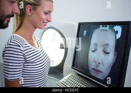 Donna che guarda MRI scan relazione sullo schermo del computer Foto Stock