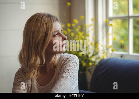 Bella Donna che guarda attraverso la finestra nella stanza vivente Foto Stock