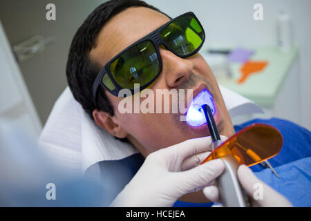 Dentista esaminare pazienti con i denti dentale luce di indurimento Foto Stock