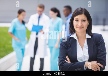 Medico donna in piedi con le braccia incrociate Foto Stock