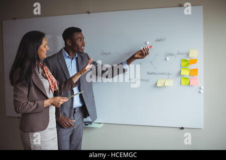 Imprenditore discutendo sulla lavagna bianca con un collega Foto Stock