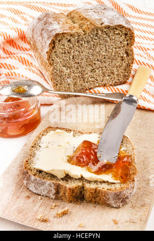 Home cotta soda irlandese pane con burro e marmellata arancione su una tavola di legno Foto Stock